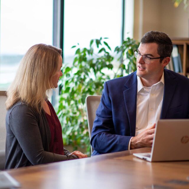 2 people sitting at a table discussing business during a meeting