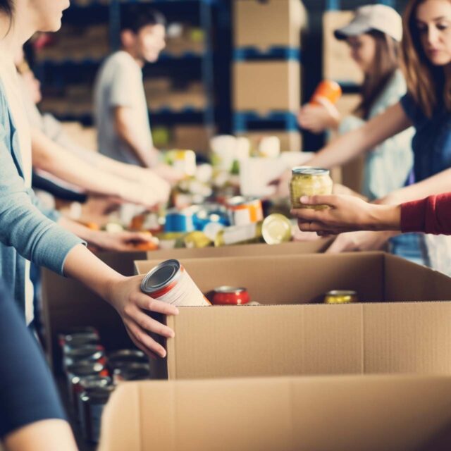 people distributing canned foods into cardboard boxes during food drive