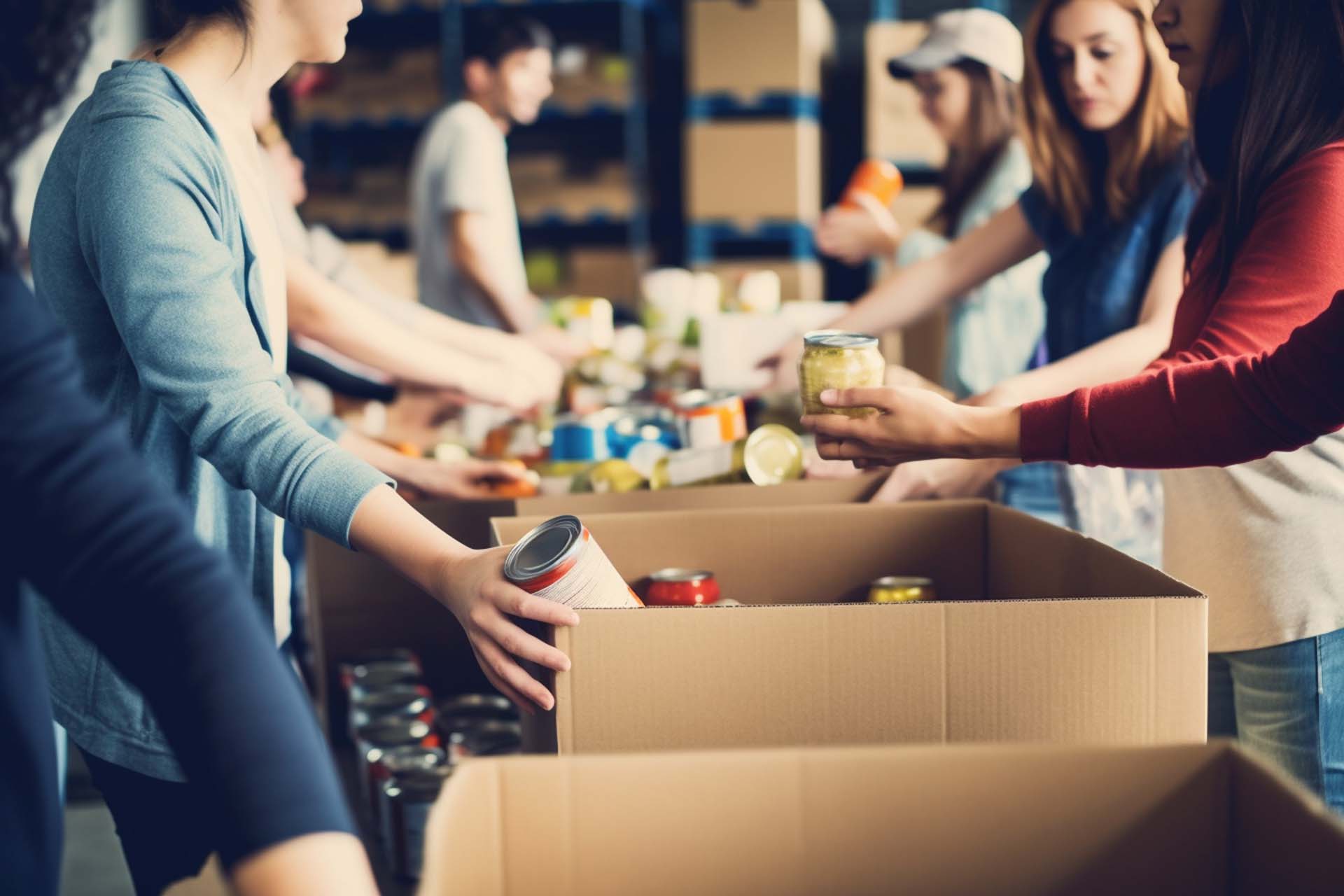 people distributing canned foods into cardboard boxes during food drive