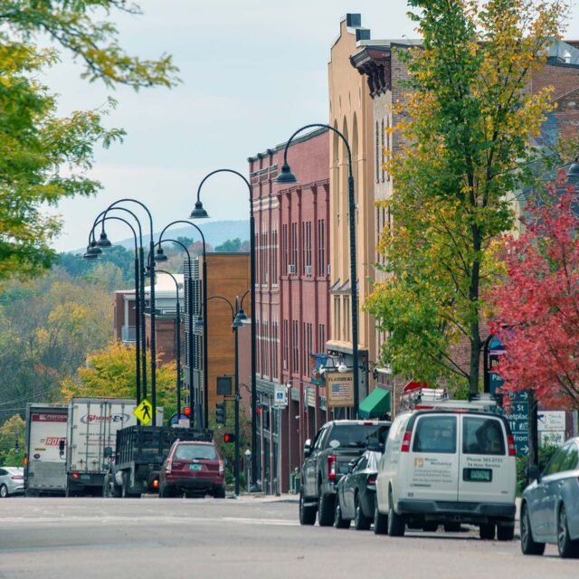 street in downtown Burlington lined with cars, street lamps, buildings and trees