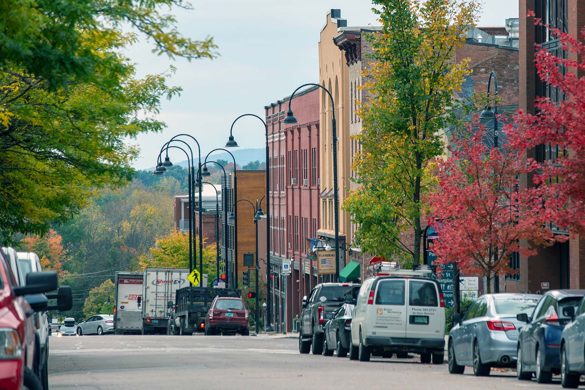 street in downtown Burlington lined with cars, street lamps, buildings and trees