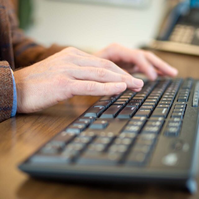 2 hands typing on computer keyboard