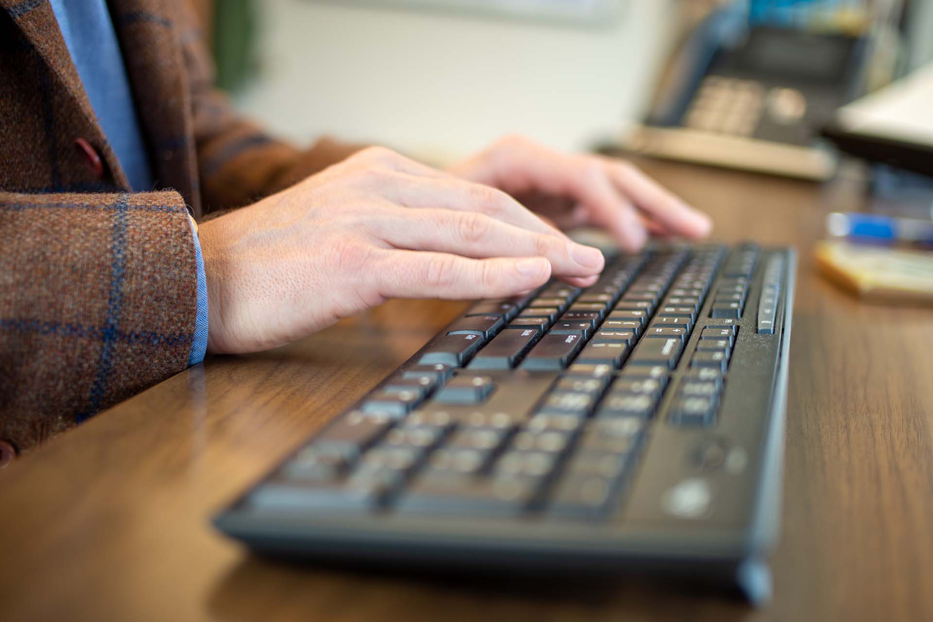 2 hands typing on computer keyboard